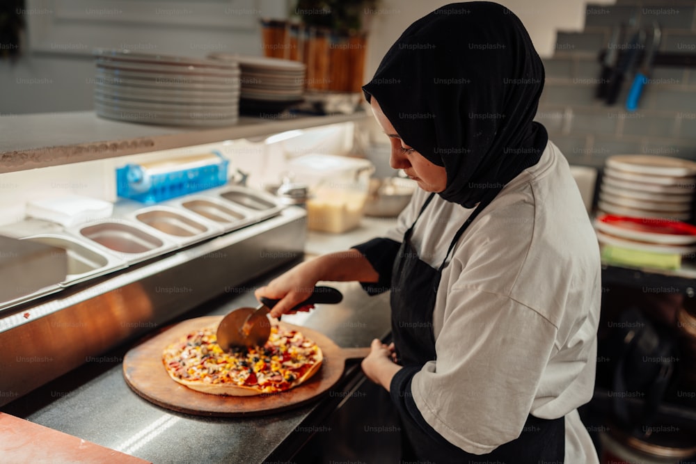 uma mulher em um hijab está fazendo uma pizza