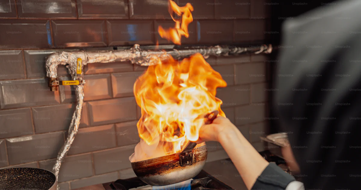 A person cooking on a stove with flames photo – Eating out Image on ...