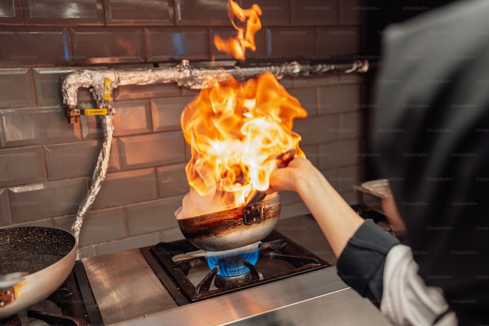 a person cooking on a stove with flames