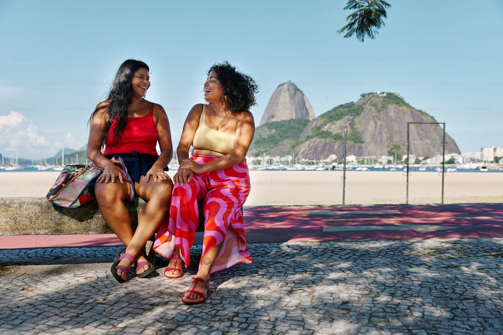 two women sitting on a stone bench talking