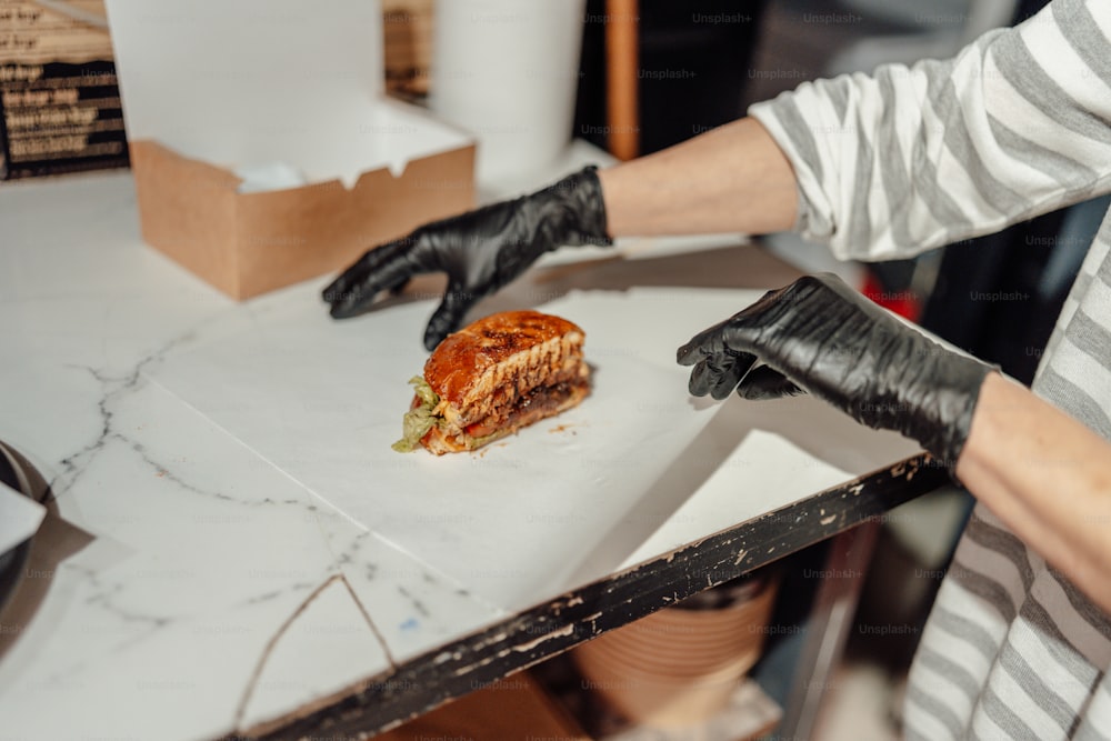 a person in black gloves is cutting a piece of food