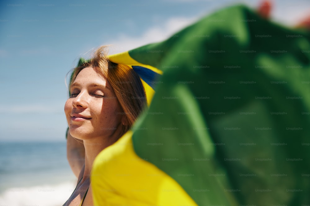 緑と黄色のタオルを持つビーチに立っている女性