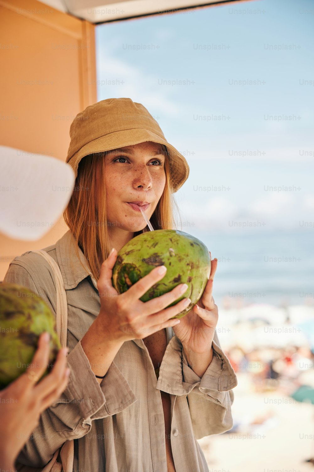 a woman in a hat holding a green fruit