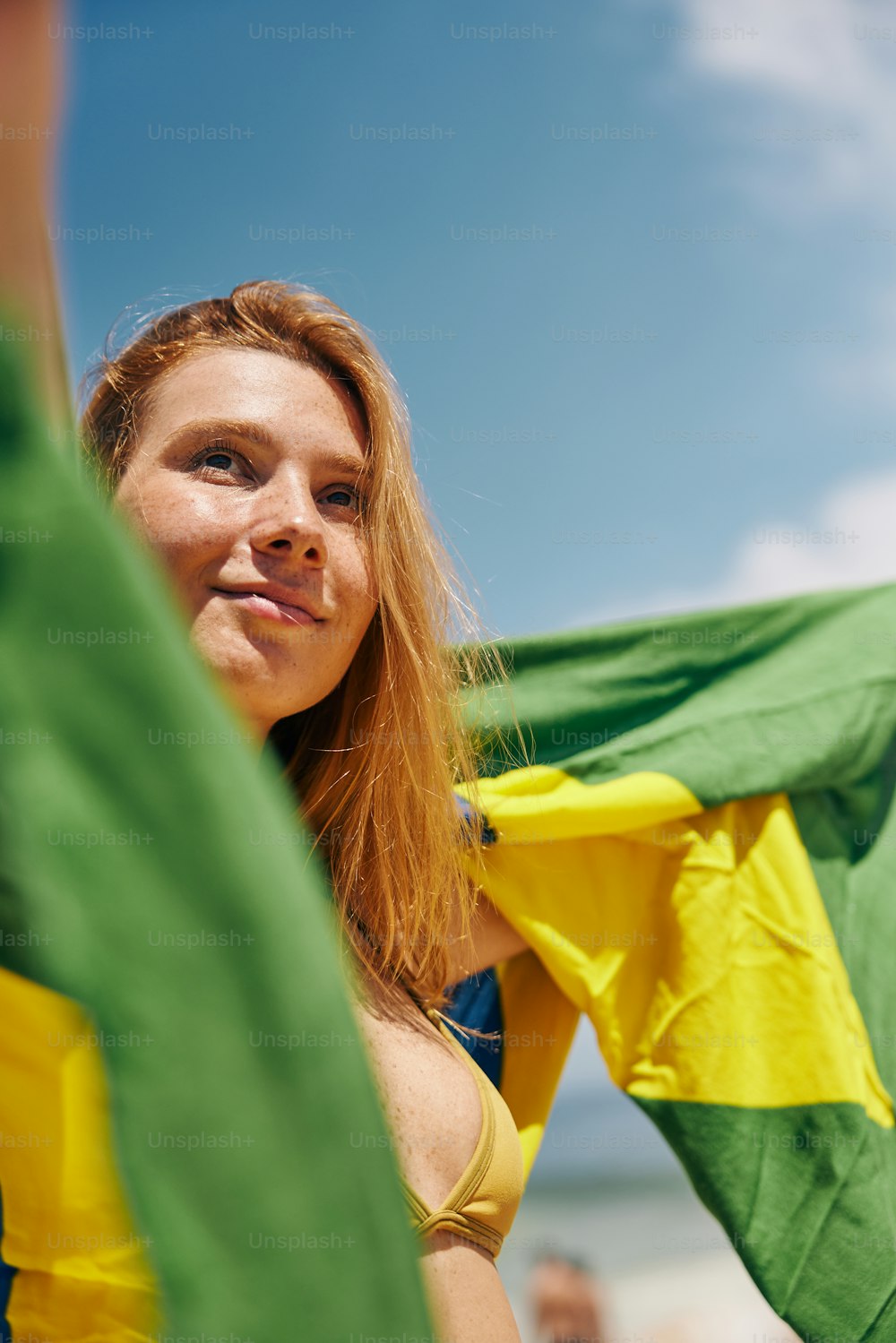 a woman in a yellow bikini holding a green and yellow flag