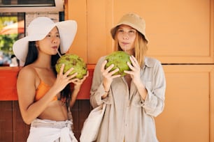 Dos hermosas mujeres de pie una al lado de la otra sosteniendo fruta verde