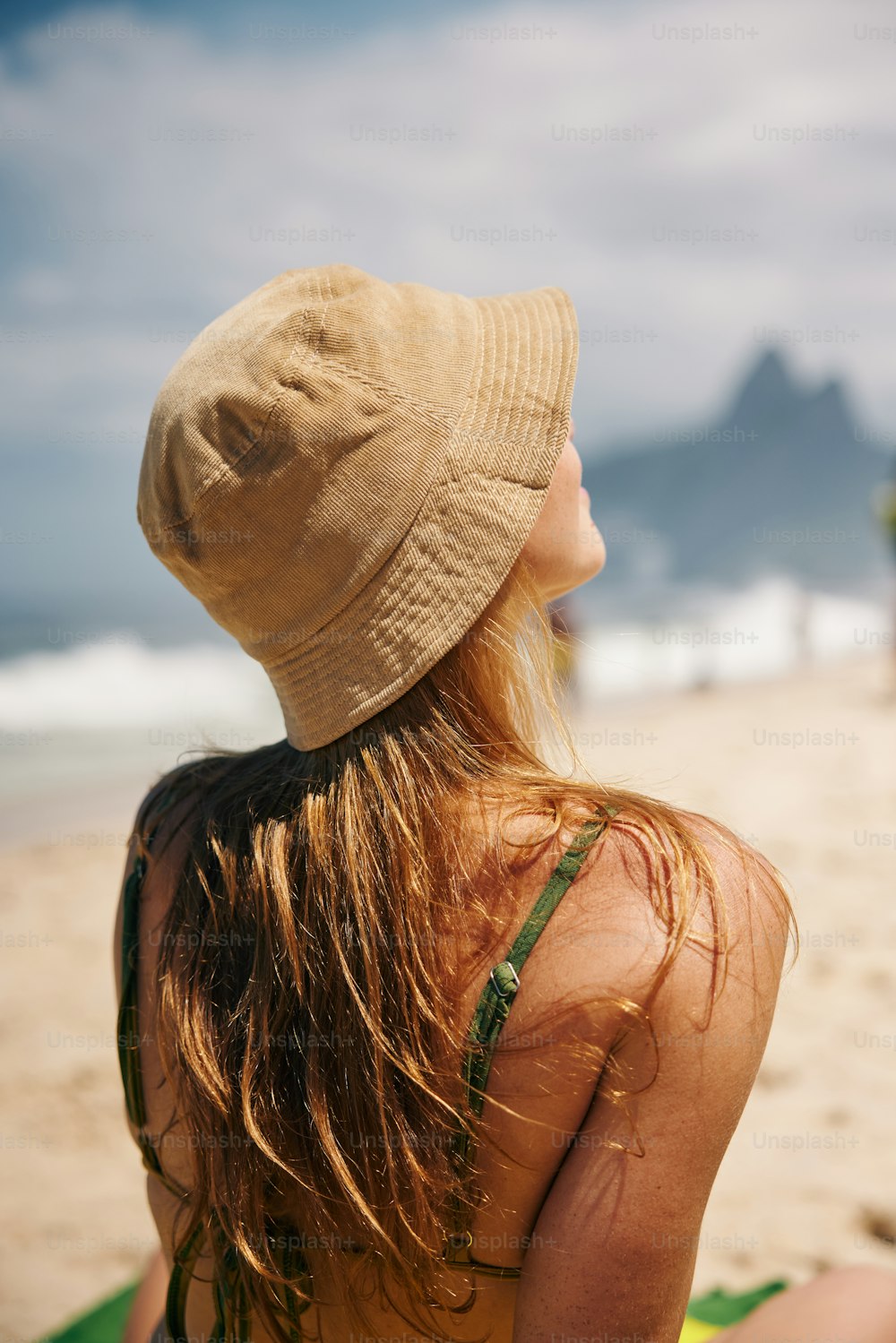 Eine Frau mit Hut sitzt am Strand