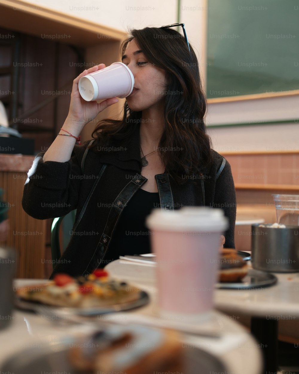 uma mulher sentada em uma mesa bebendo de um copo