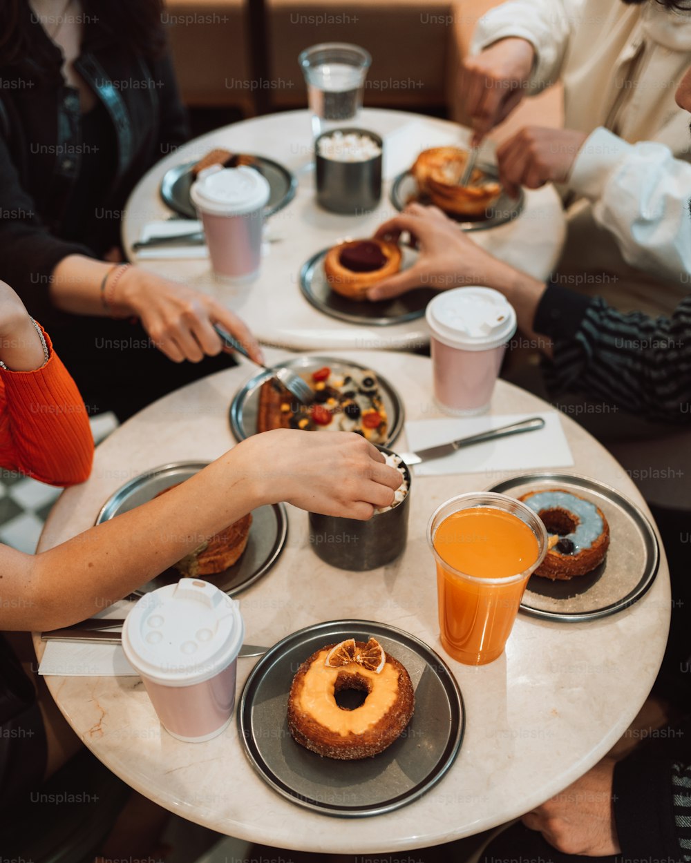 a group of people sitting at a table eating doughnuts