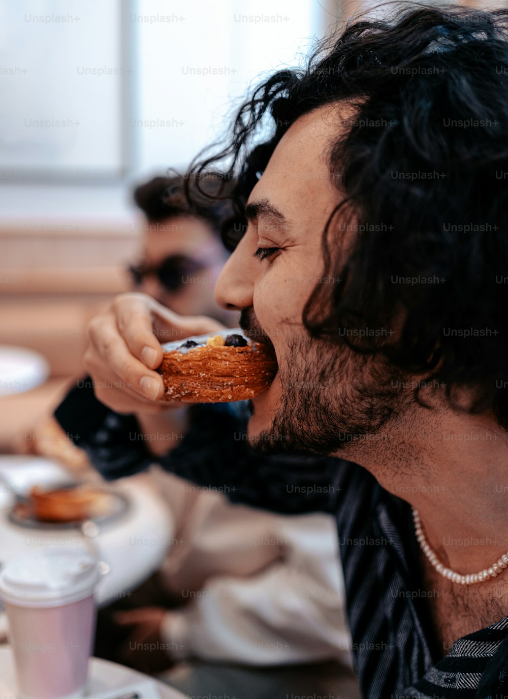 a man with long hair eating a doughnut