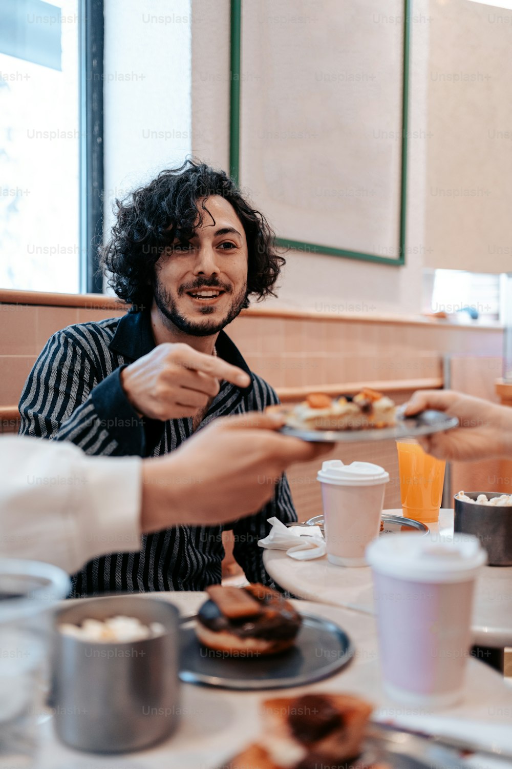 a man holding a plate of doughnuts at a table