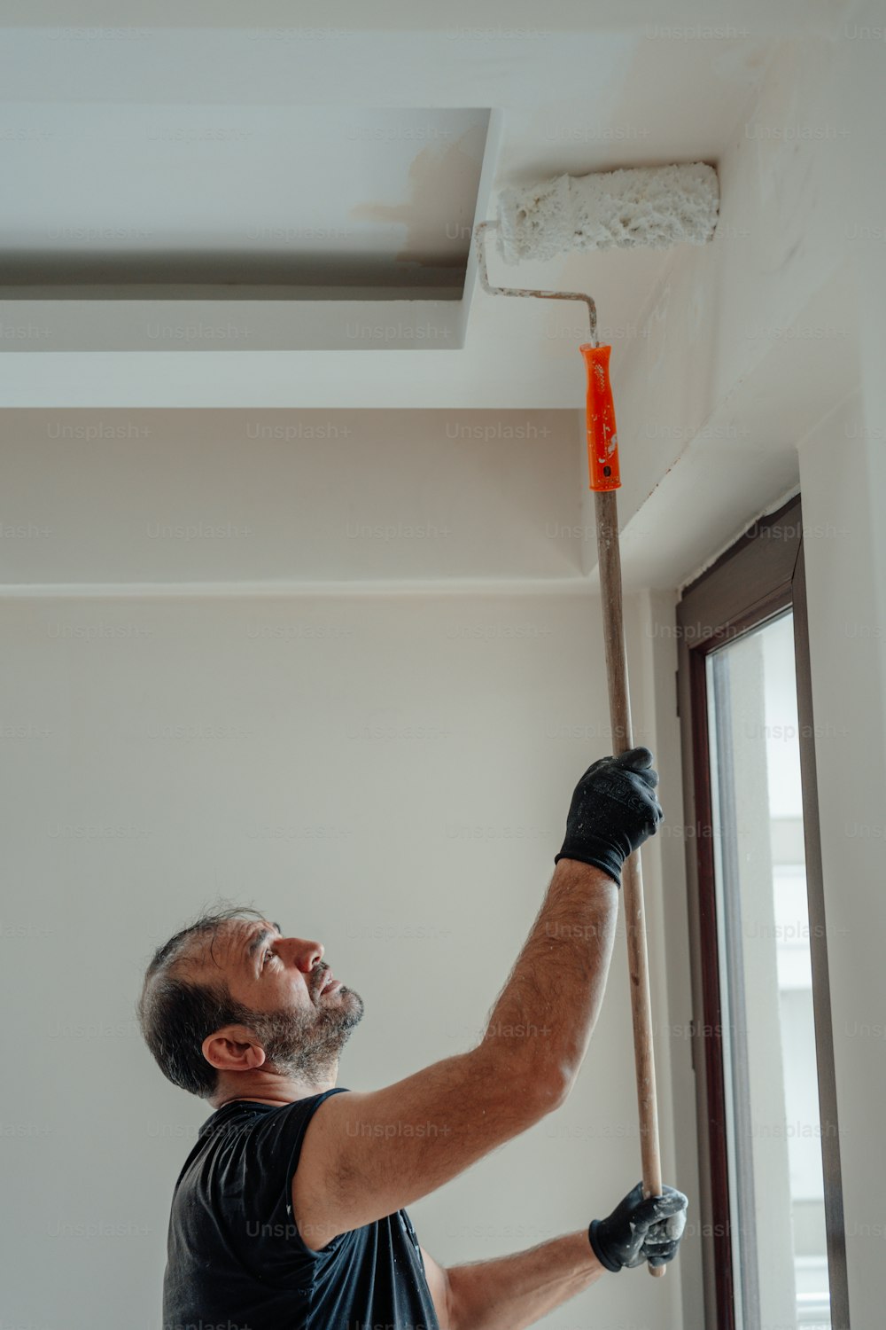 a man is painting a ceiling with a paint roller