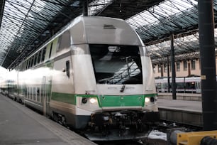 a white and green train pulling into a train station