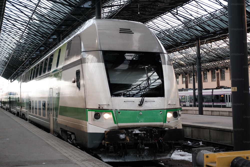 Un treno bianco e verde che entra in una stazione ferroviaria