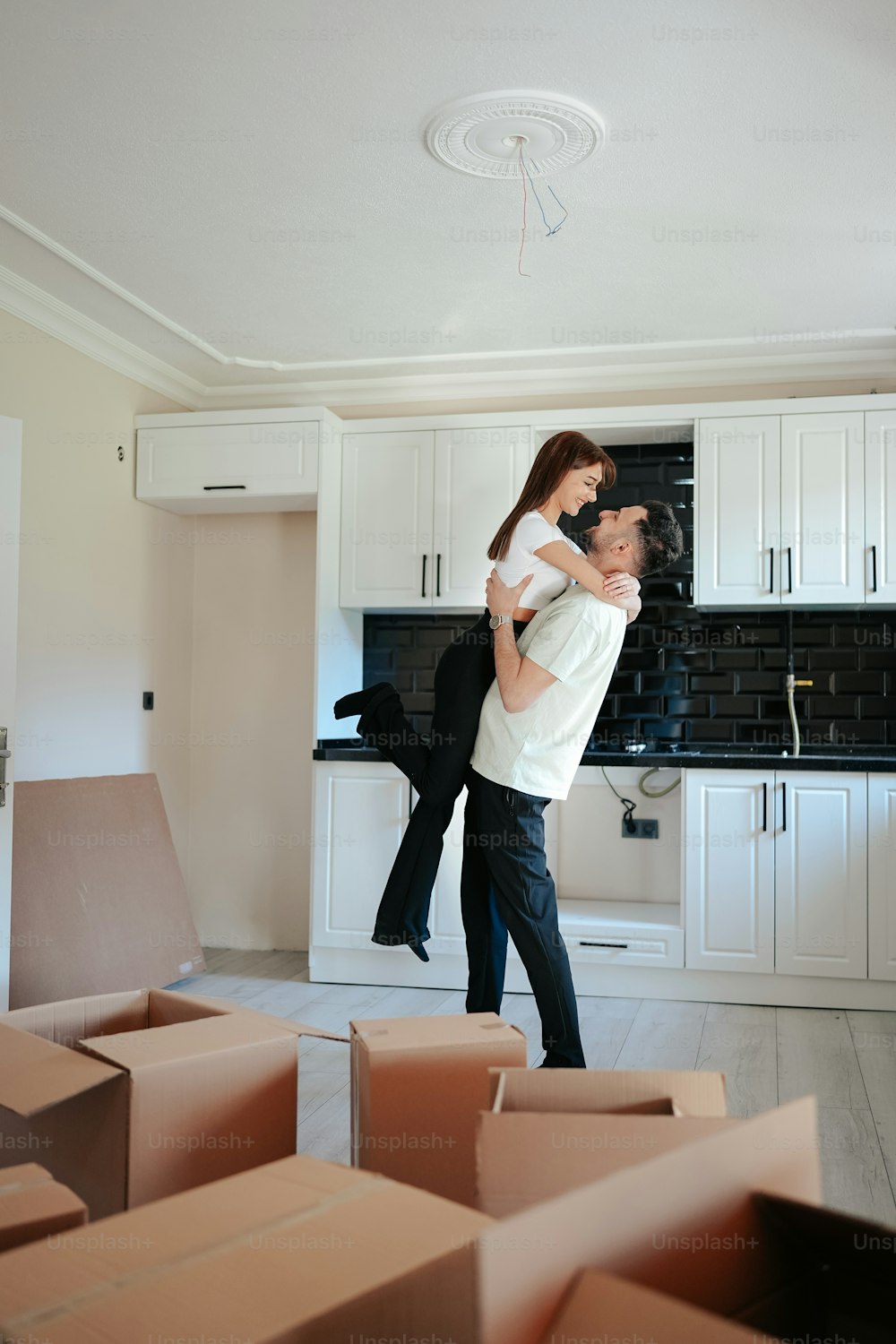 a man carrying a woman in a room full of boxes