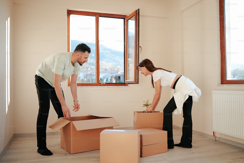 a man and a woman moving boxes into a new home
