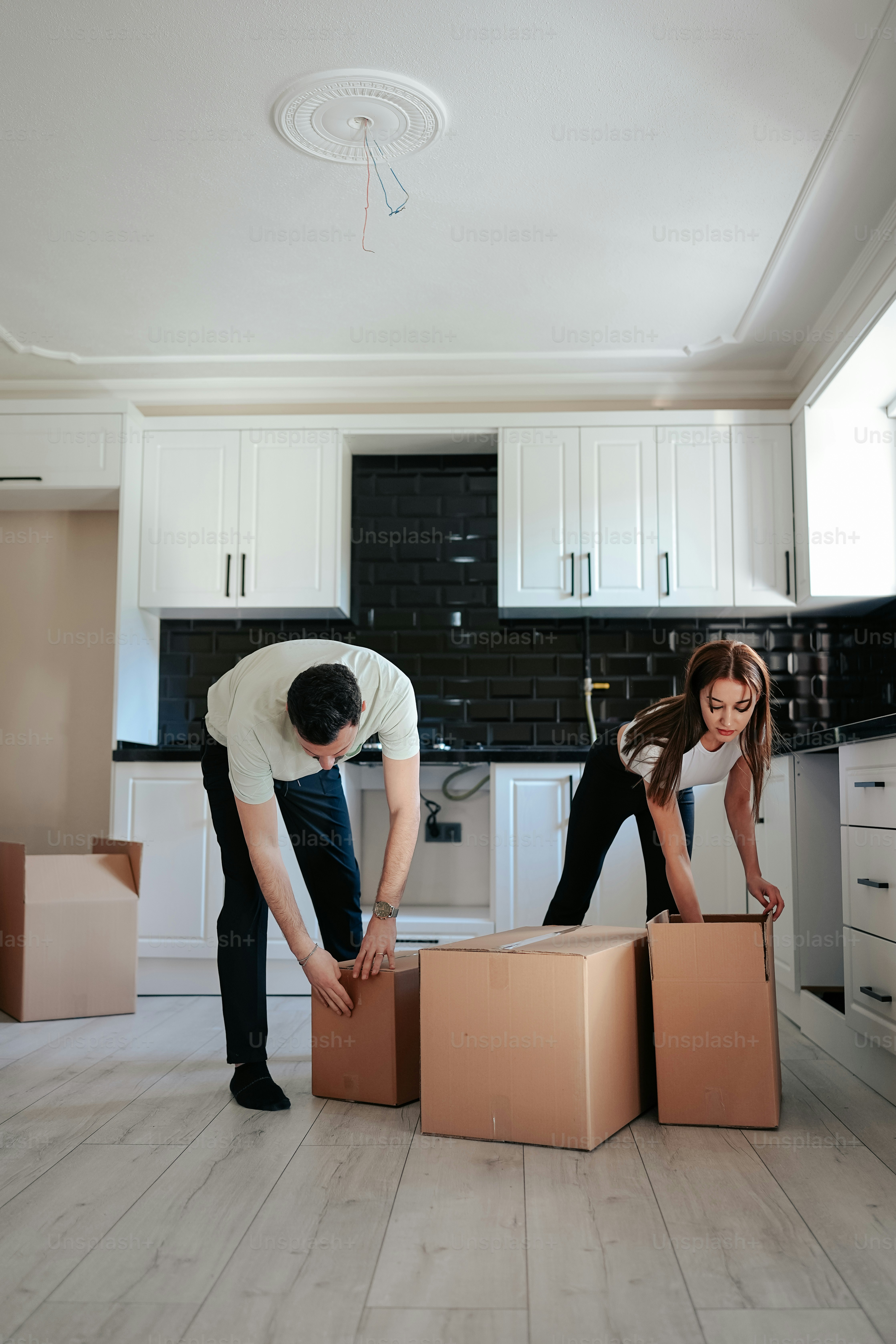 a man and a woman unpack boxes in a kitchen