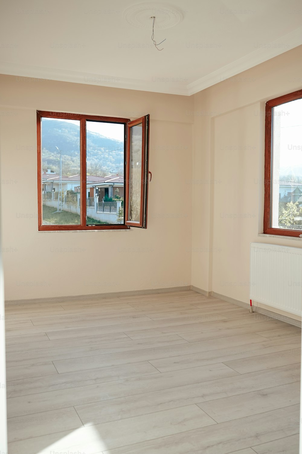 una stanza vuota con due finestre e un pavimento in legno duro