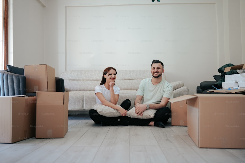 a man and a woman sitting on the floor surrounded by boxes