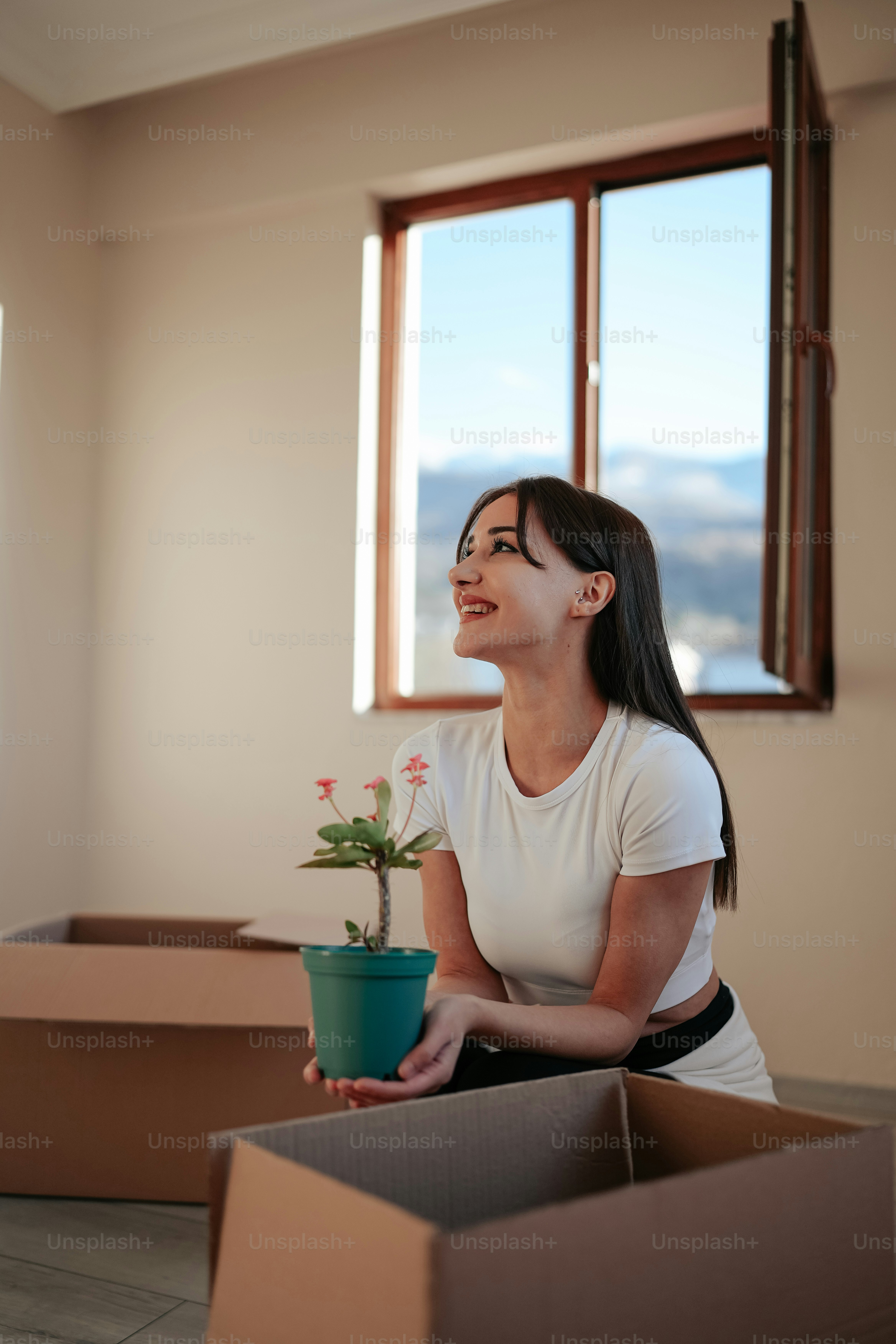 Eine Frau, die eine Topfpflanze in einer Kiste hält
