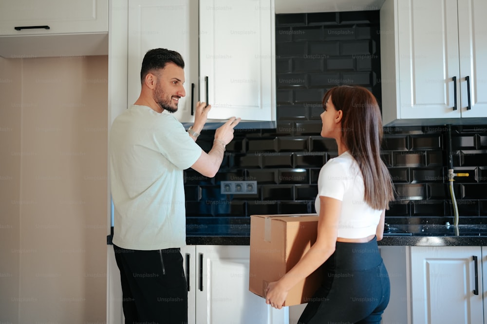 a man and a woman moving boxes in a kitchen