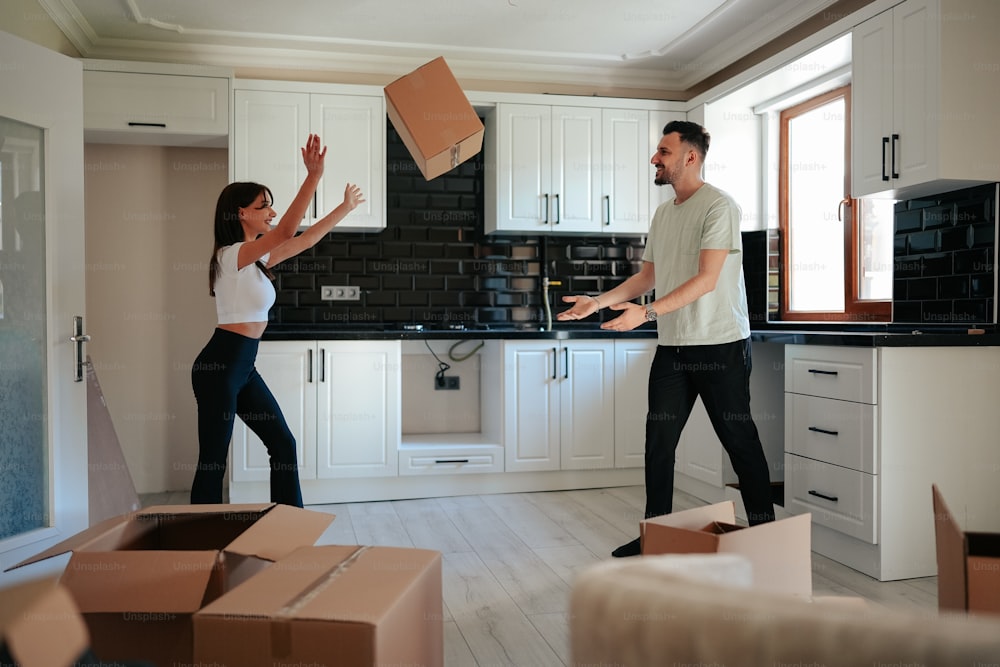 a man and a woman moving boxes in a kitchen