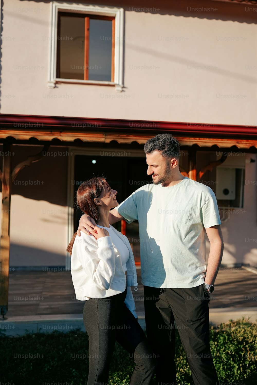 a man standing next to a woman in front of a house