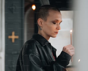 a woman in a leather jacket holding a candle