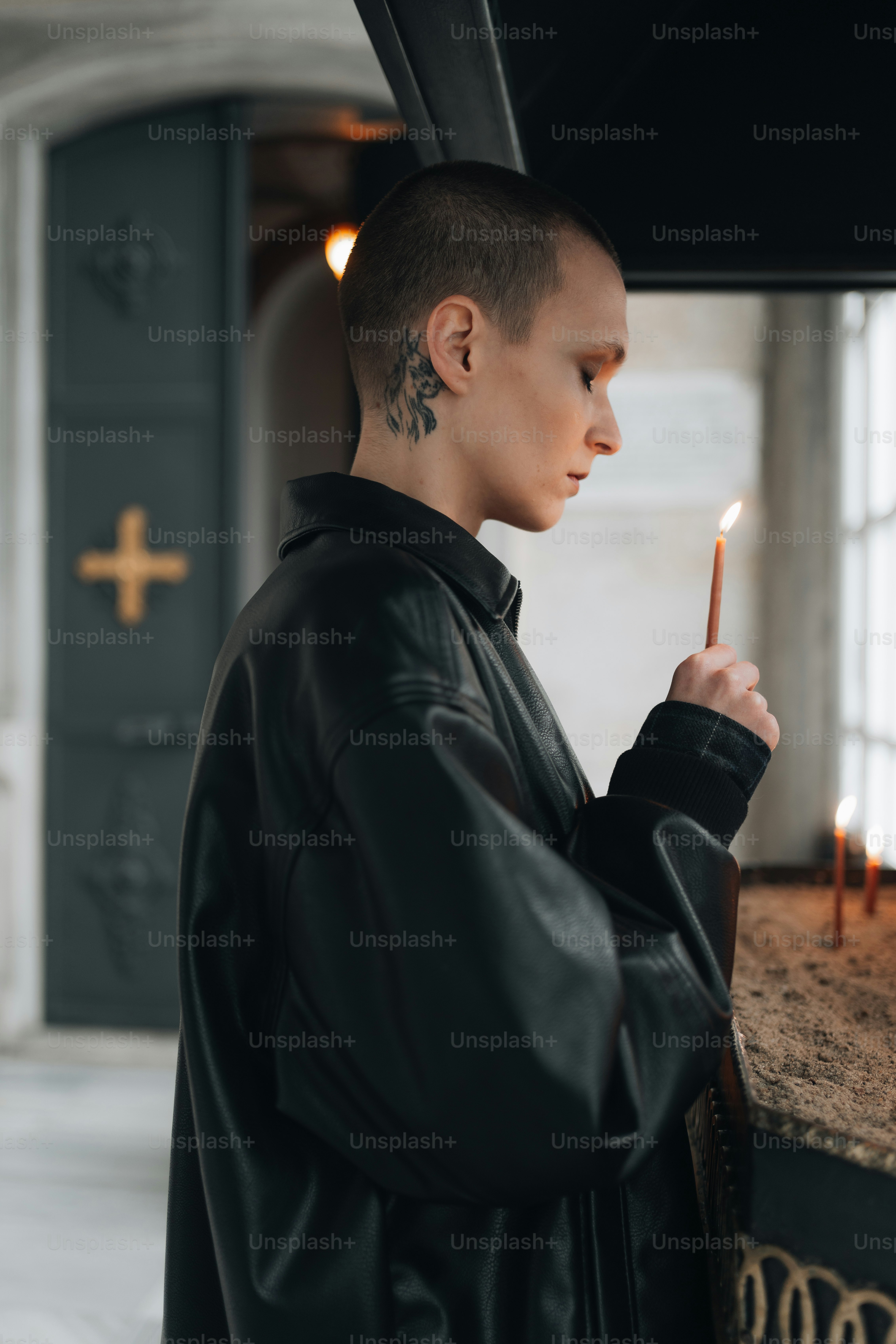 a man in a black leather jacket holding a lit candle