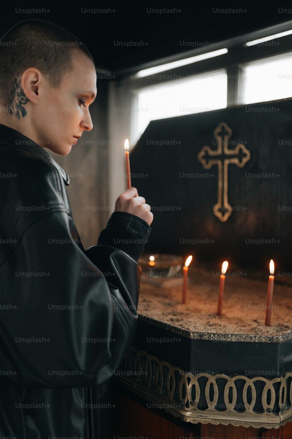 um homem segurando uma vela na frente de uma cruz