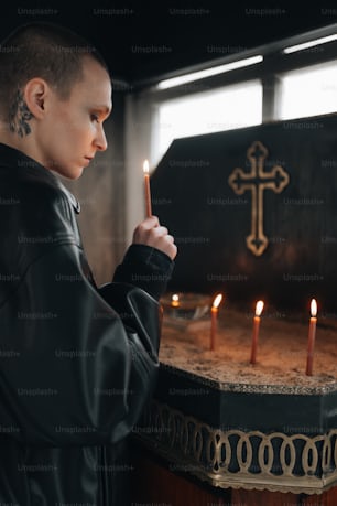 a man holding a candle in front of a cross