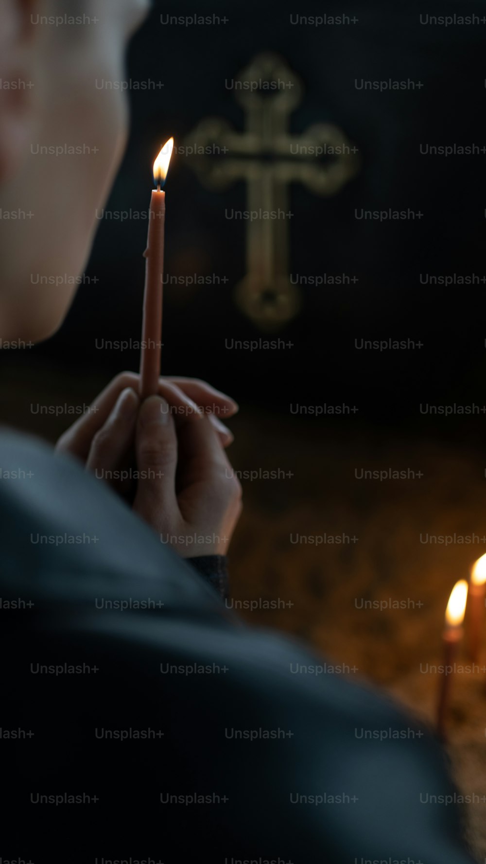 a person holding a candle in front of a cross