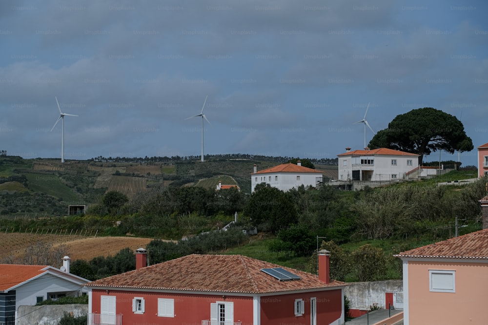 a row of houses with wind turbines in the background