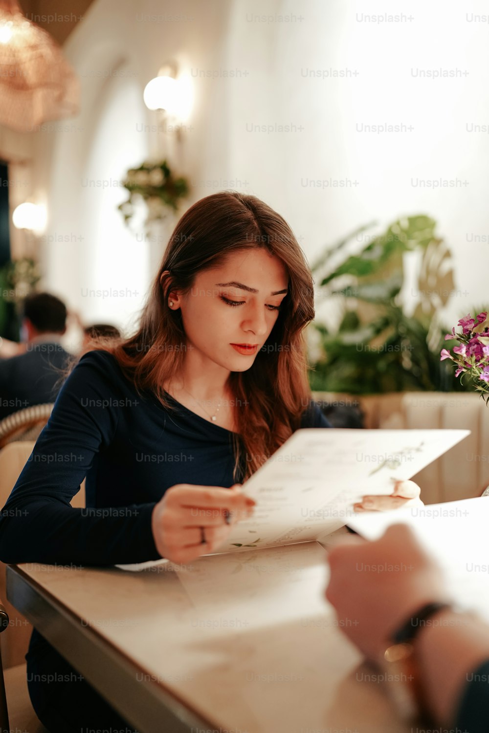 a woman sitting at a table reading a paper