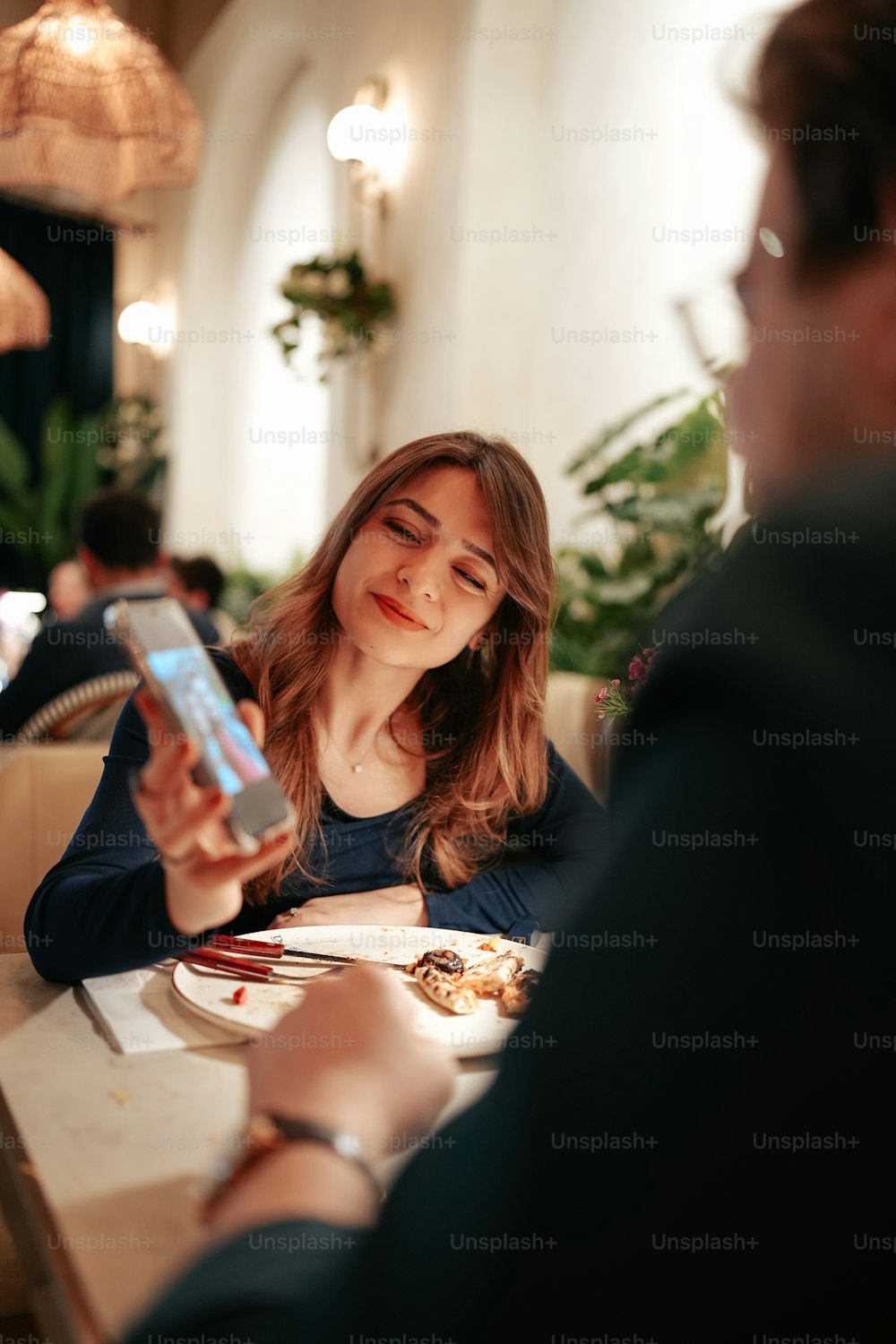 a woman sitting at a table looking at her cell phone