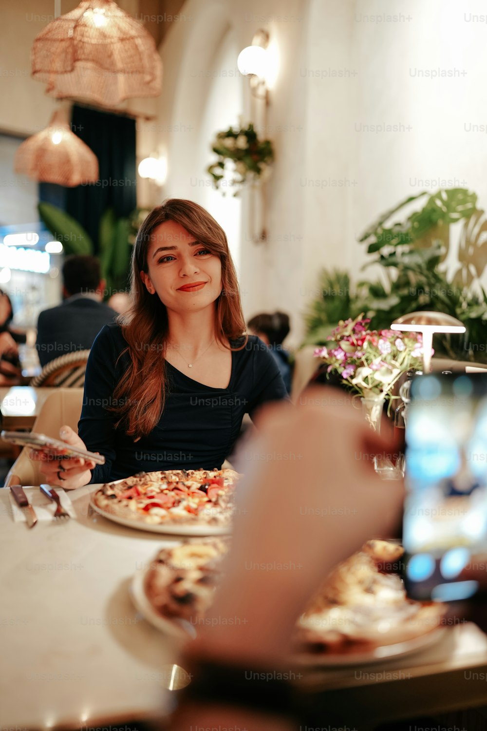 a woman sitting at a table with a plate of pizza