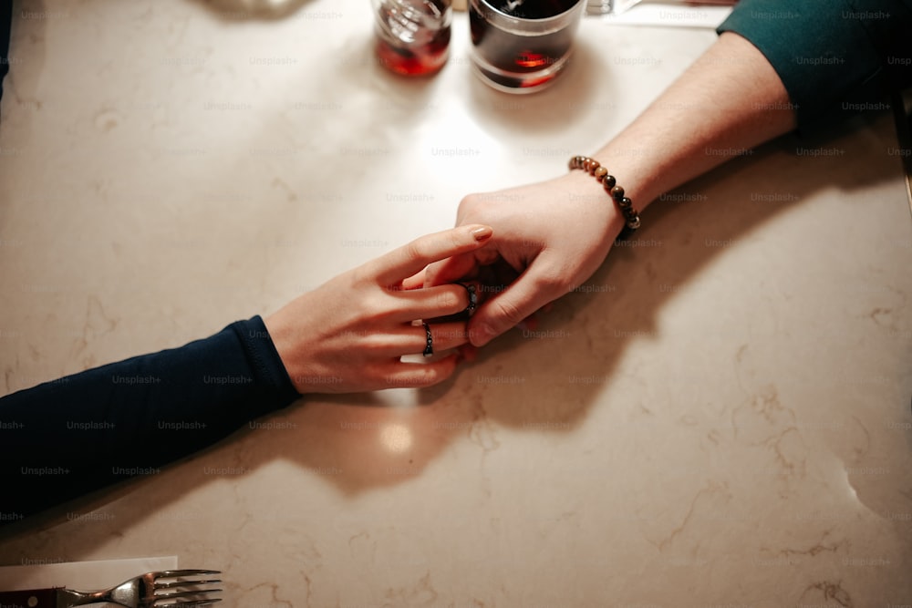 a close up of two people holding hands at a table