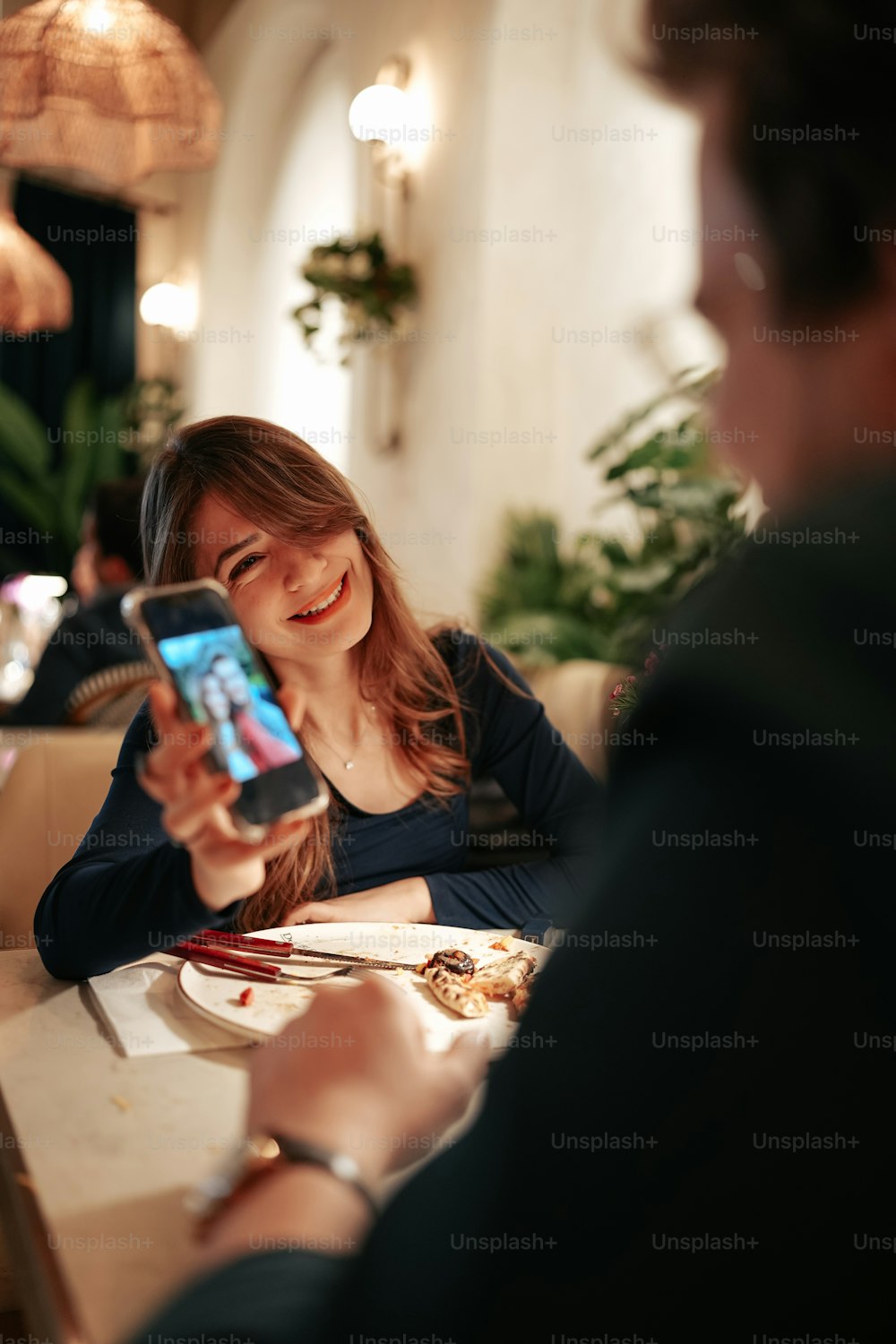 uma mulher sentada em uma mesa com um telefone celular