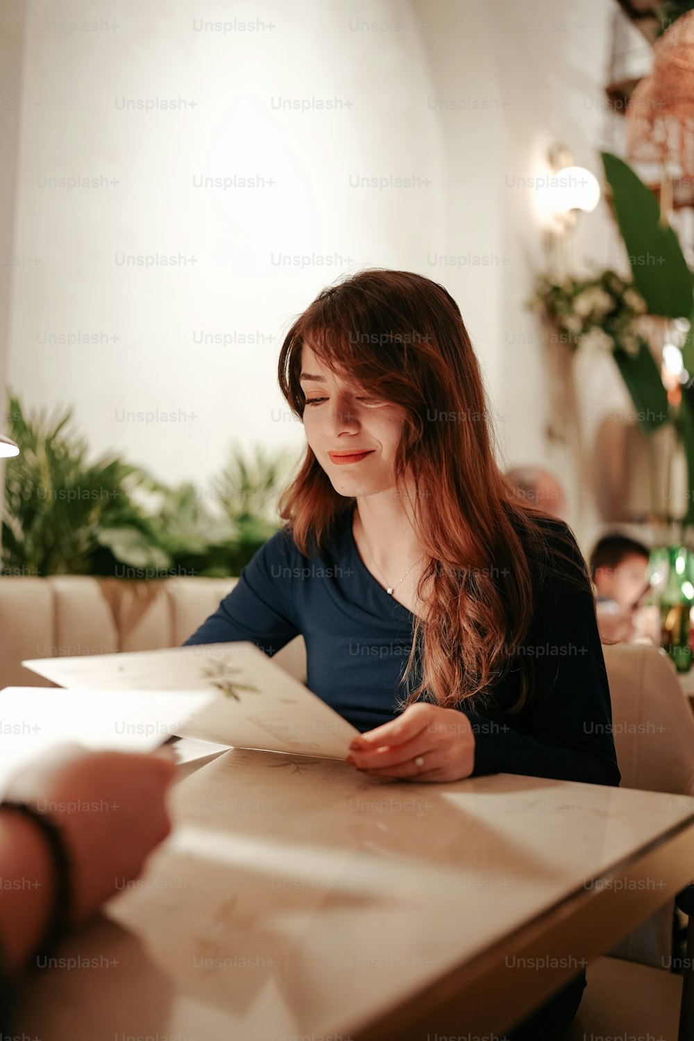 a woman sitting at a table reading a book
