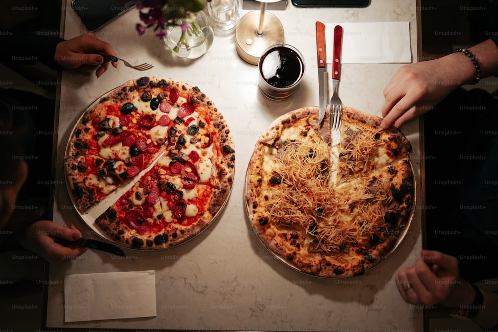 Un par de pizzas sentadas encima de una mesa