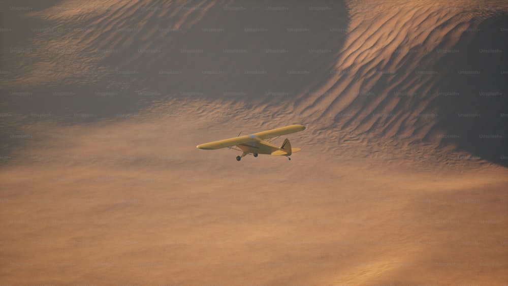 a small airplane flying over a sandy area