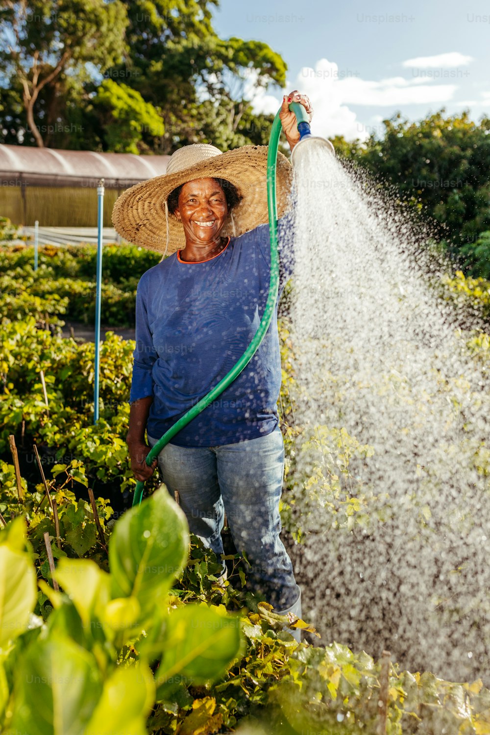 a man in a straw hat holding a hose and spraying water