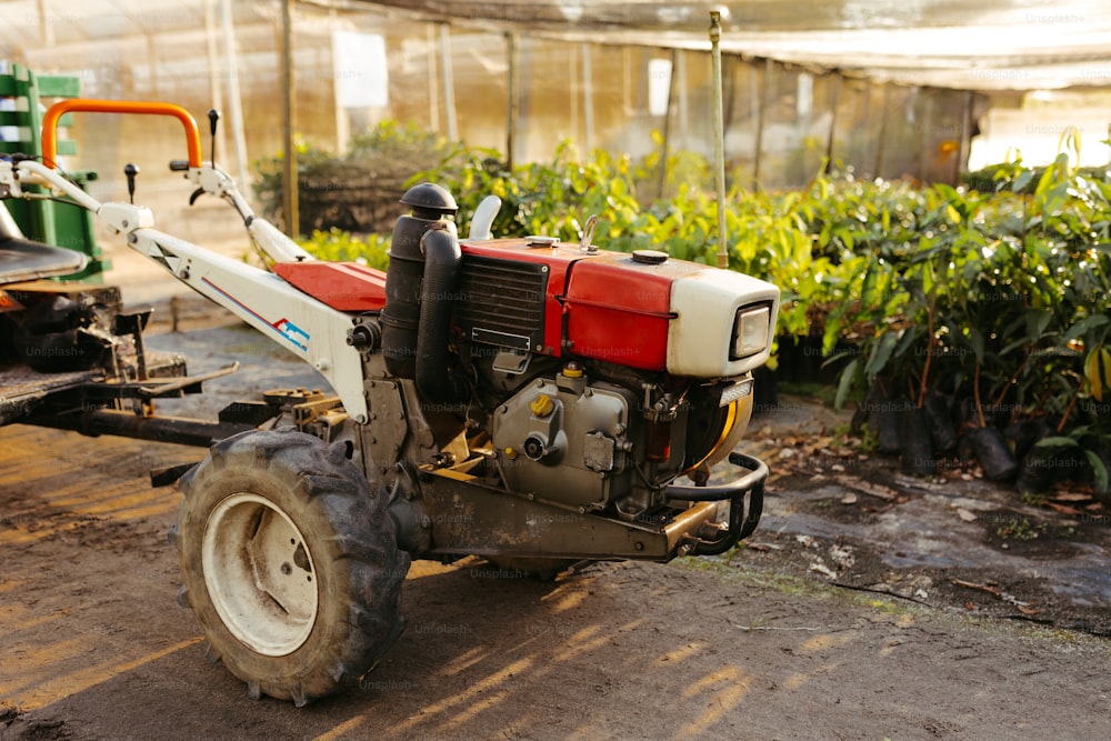 a red and white tractor parked next to a green house
