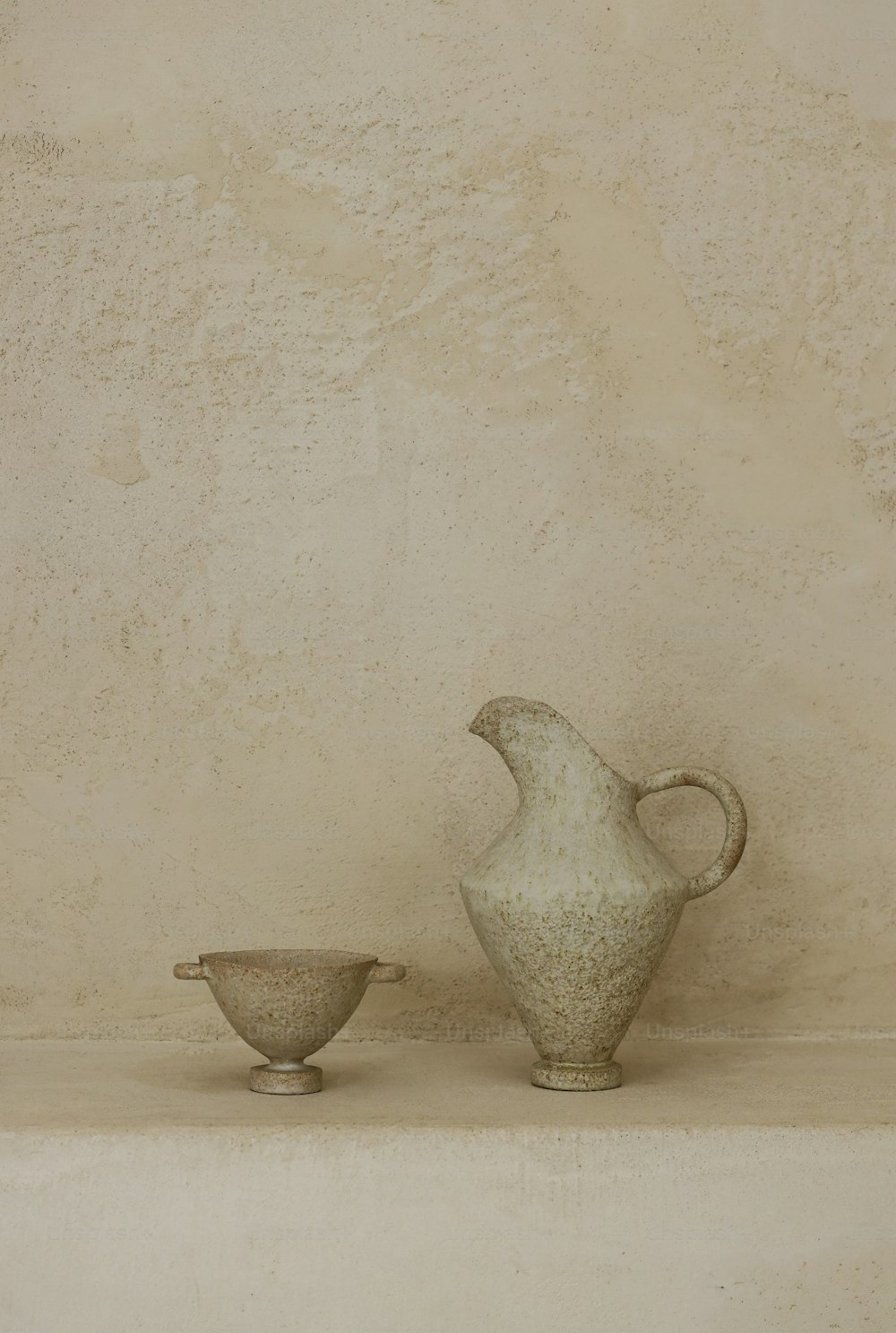 a white vase and a bowl sitting on a shelf