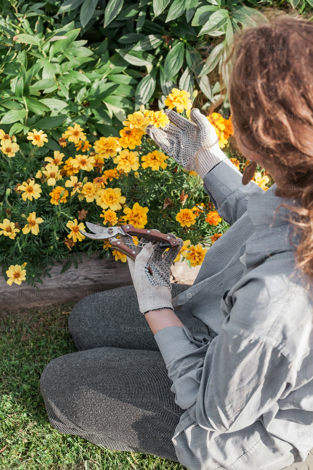 a woman sitting on the ground in front of flowers