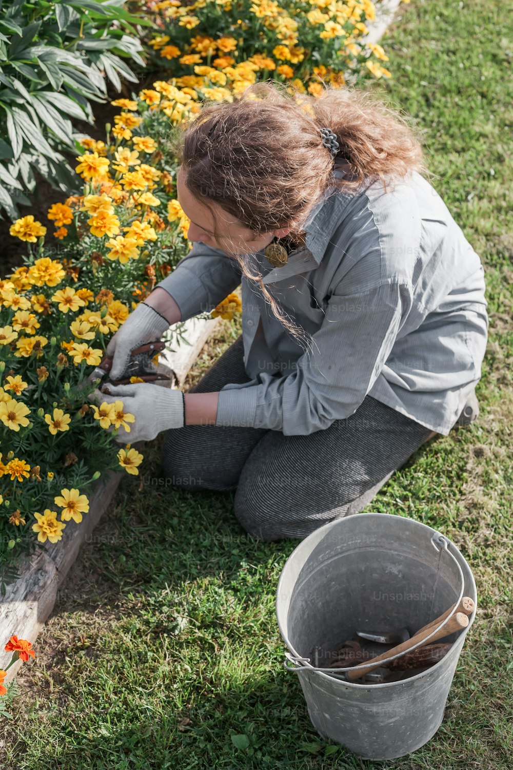 a woman kneeling down in front of a flower garden