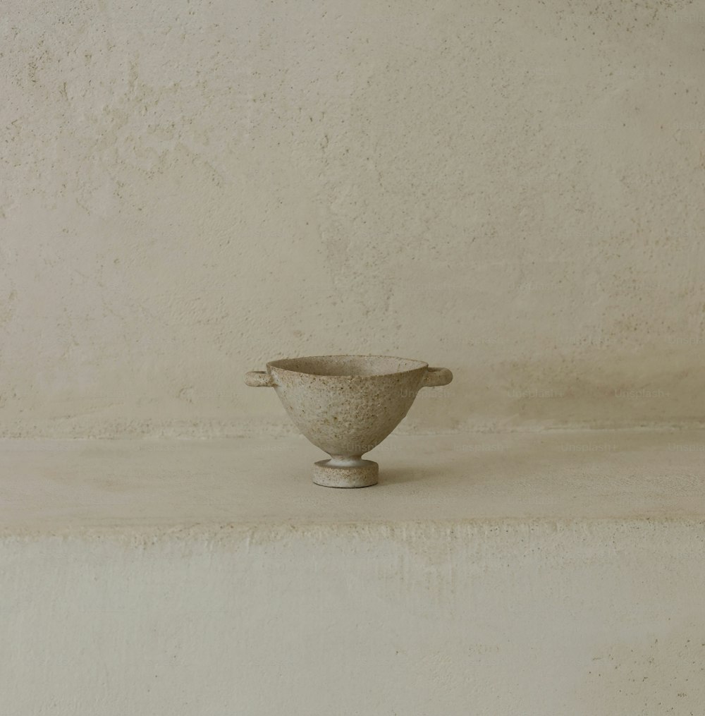 a white bowl sitting on top of a cement wall