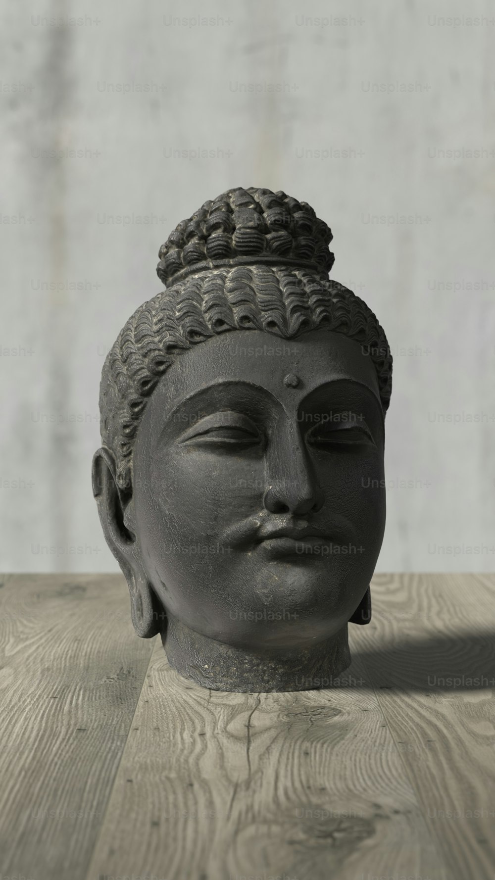 a gray buddha head sitting on top of a wooden table
