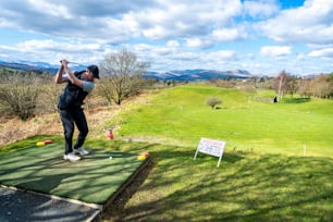 a man swinging a golf club on top of a green field