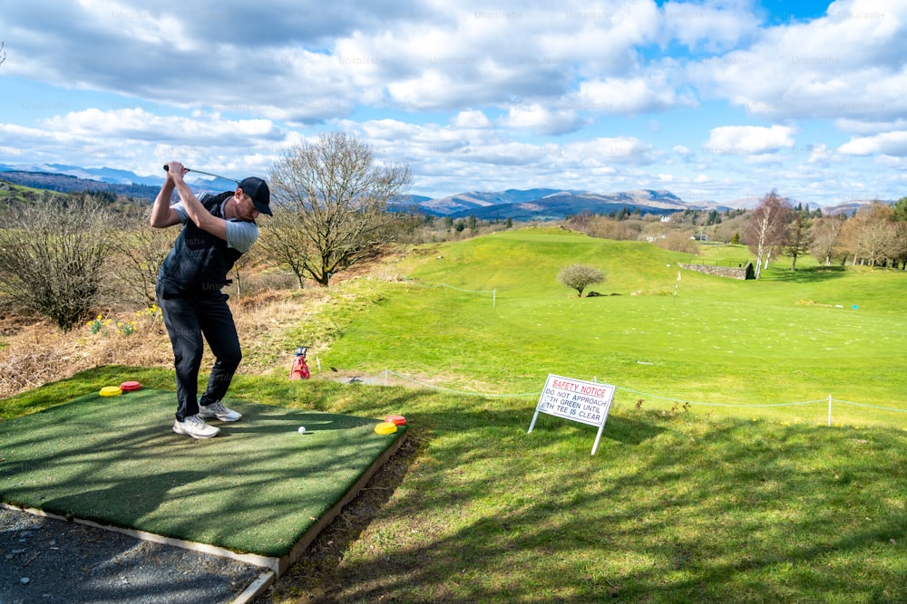 a man swinging a golf club on top of a green field