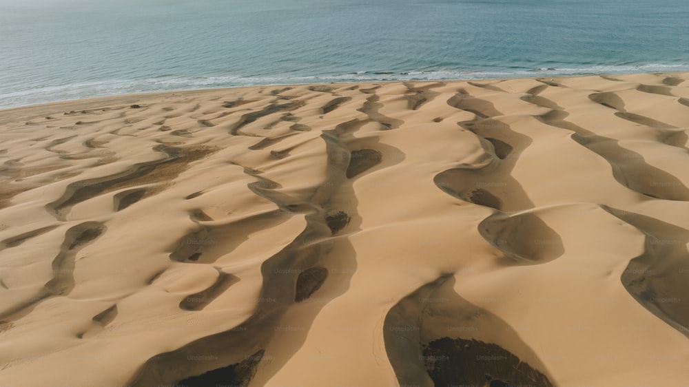 Una playa de arena con un cuerpo de agua en el fondo